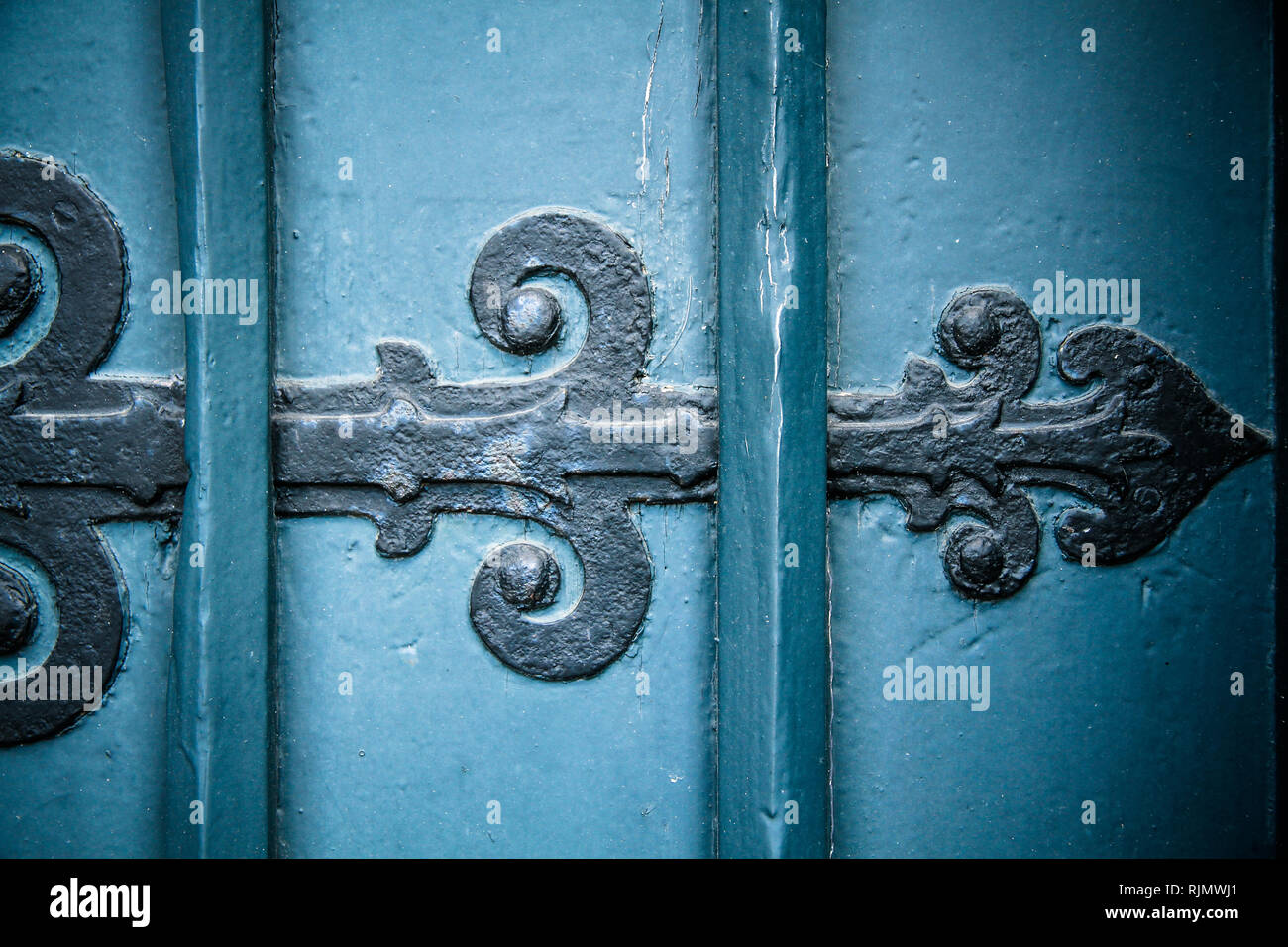 Old vintage and rusty black iron door ornament arrow on heavy and massive antique style blue wood door. Stock Photo