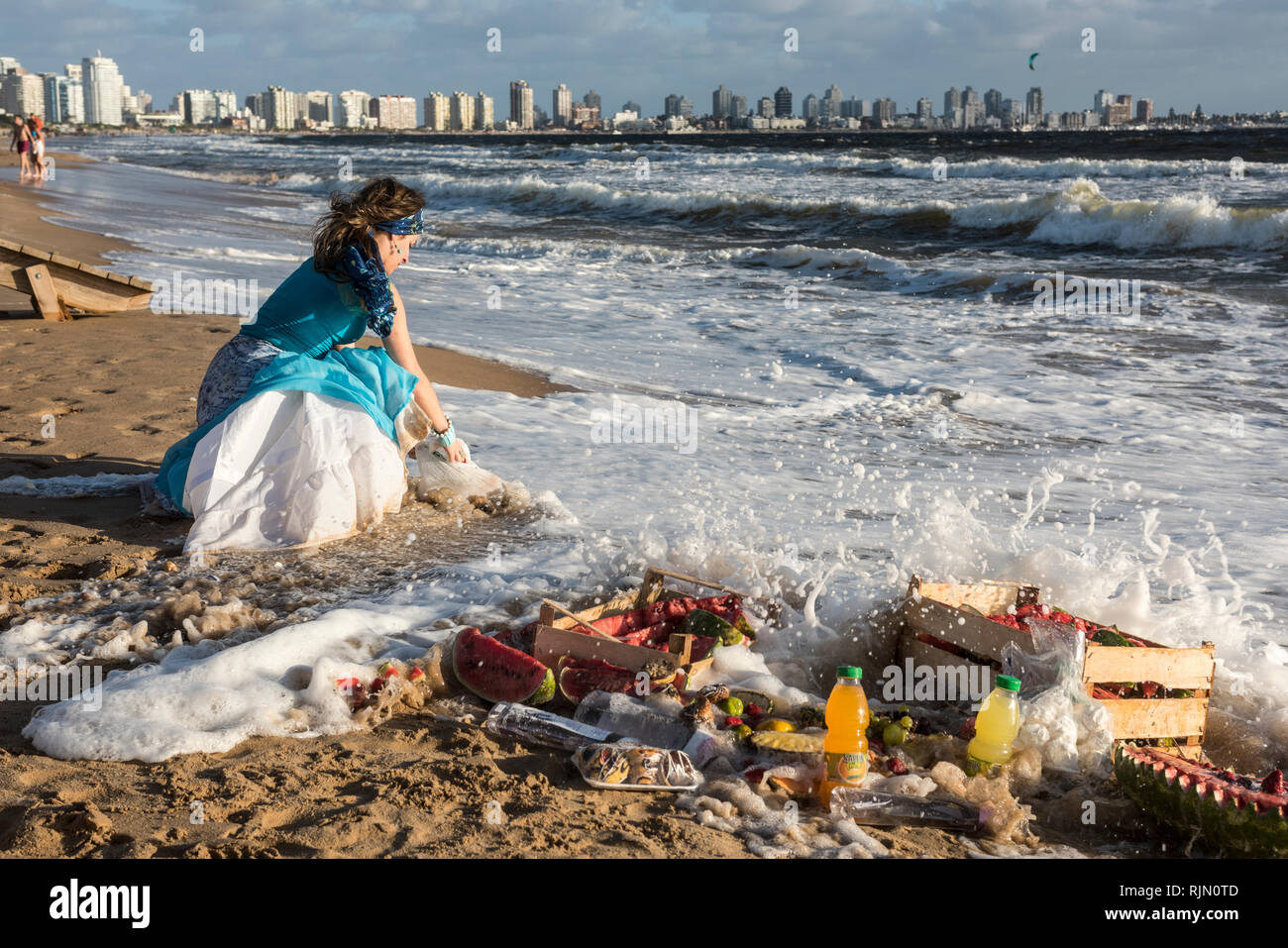 Maldonado, Uruguay - February 2, 2019: Woman from the Umbanda church brings fruits and sweets to Orisha Yemanja (Iemanja) on the Playa Mansa beach in  Stock Photo