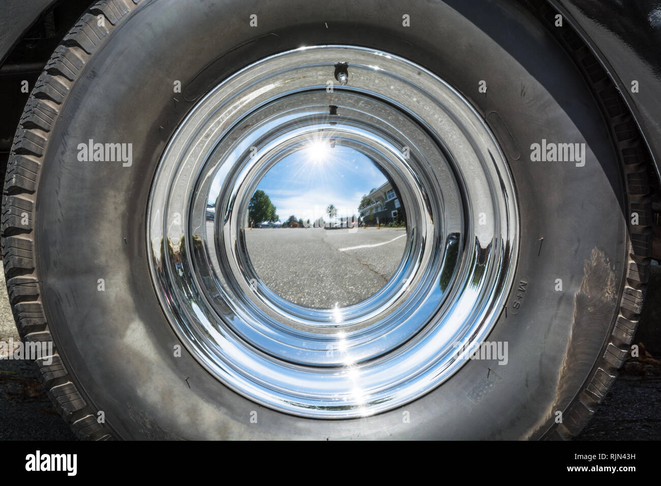 Black tire and chrome mirror cover on the wheel of vintage car. Stock Photo