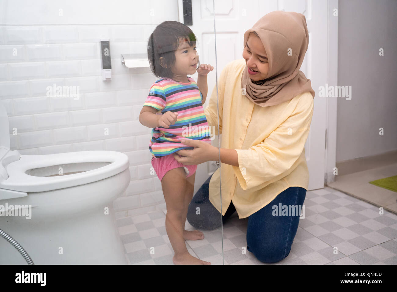 muslim mother help her kid to use toilet Stock Photo