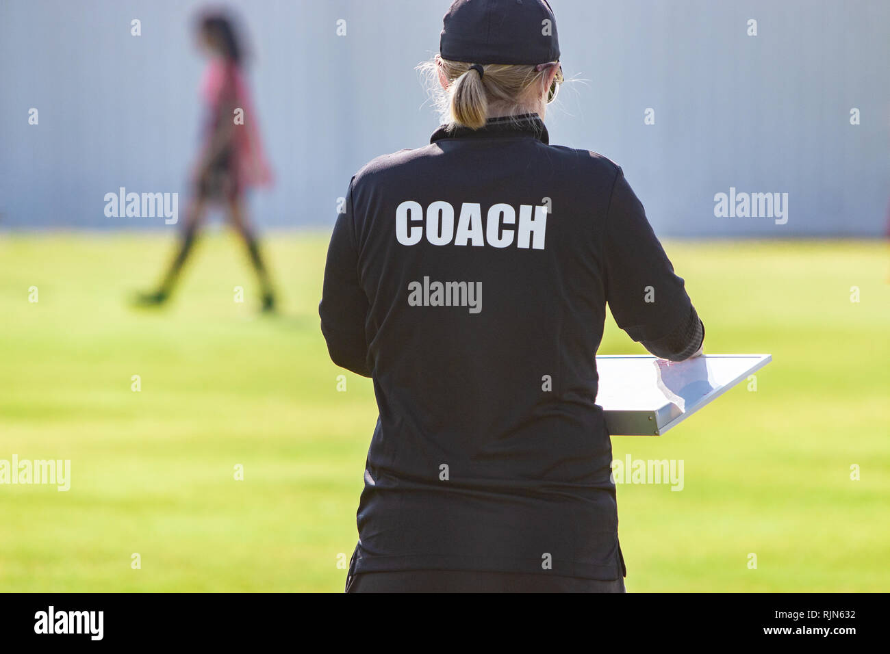 Back view of sport coach in COACH shirt at an outdoor sport field Stock Photo