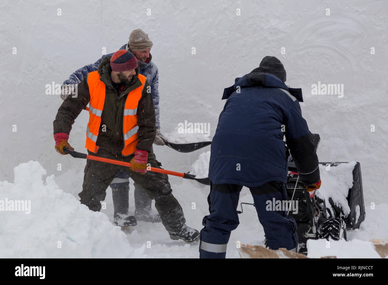 Workers remove snow in a blizzard using a snowplow Stock Photo - Alamy