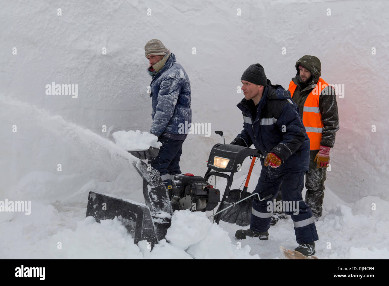 Workers remove snow in a blizzard using a snowplow Stock Photo - Alamy