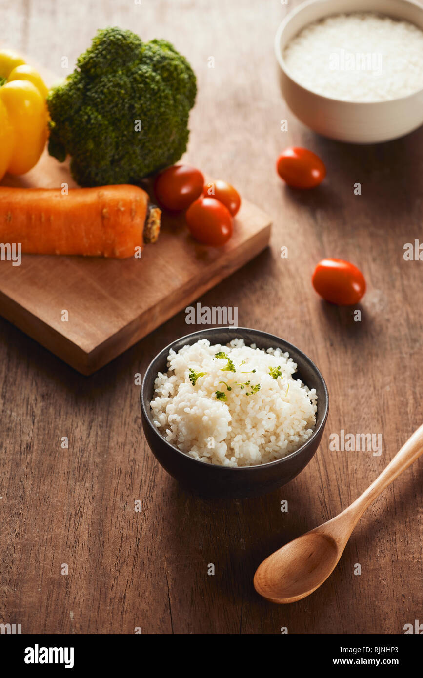 Grains of rice in a wooden bowl and ingredients for a vegetarian recipe ...