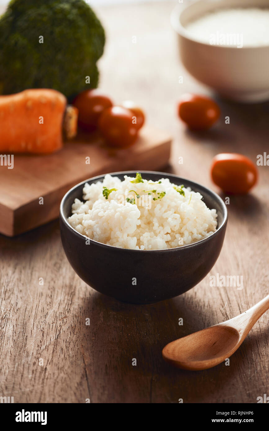 Grains of rice in a wooden bowl and ingredients for a vegetarian recipe ...