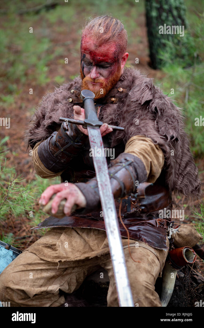 Real viking sharpening his sword with a stone. Ready for the fight 