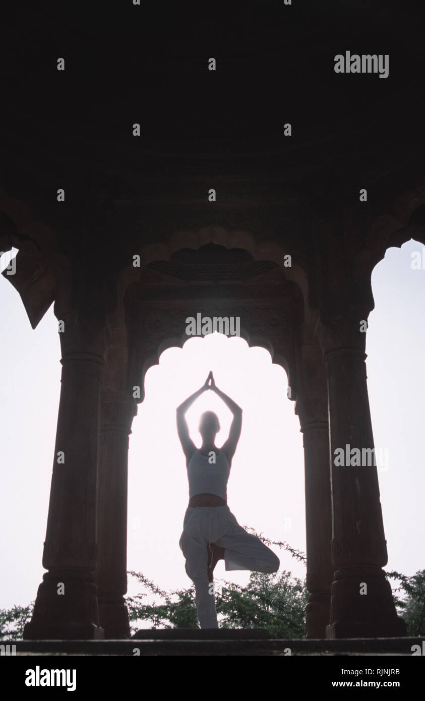 Caption: Khimsar, Rajasthan, India - Apr 2003. A woman performing yoga asanas in the ruins of a Mughol pavillion in Khimsar, a small village in the he Stock Photo