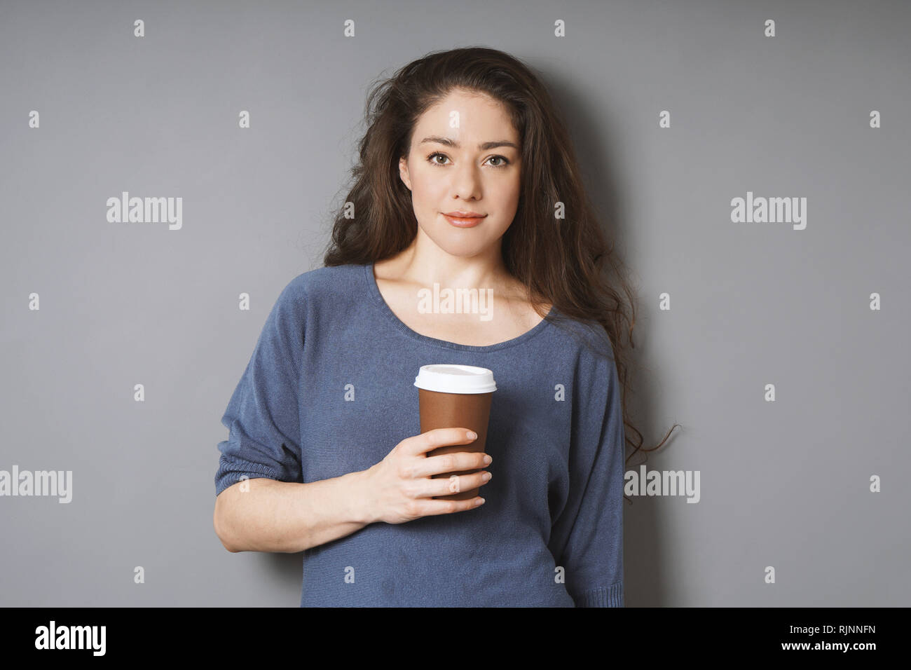 relaxed young woman holding coffee to go in disposable cup Stock Photo