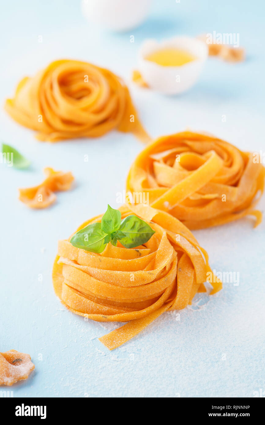 Fresh raw uncooked homemade twisted pasta tagliatelle with egg yolk and ...