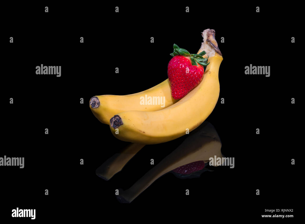 Two Bananas and strawberry Bananas and strawberry on a black background Stock Photo