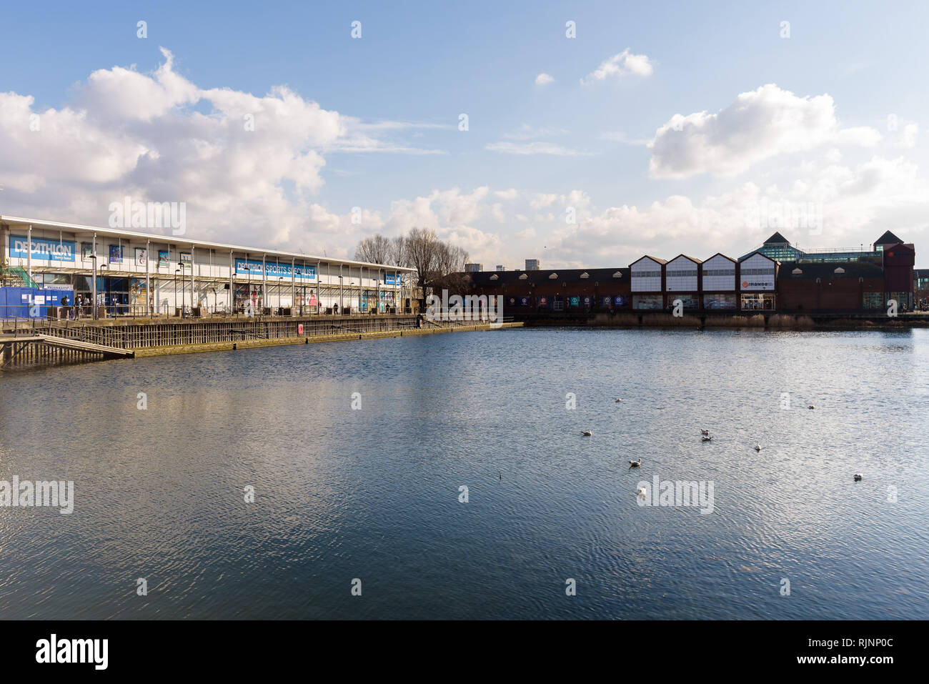 View of Decathlon Sports Centre and Surrey Quays Shopping Centre across the pond in Canada Water on a sunny day. London, England. Stock Photo