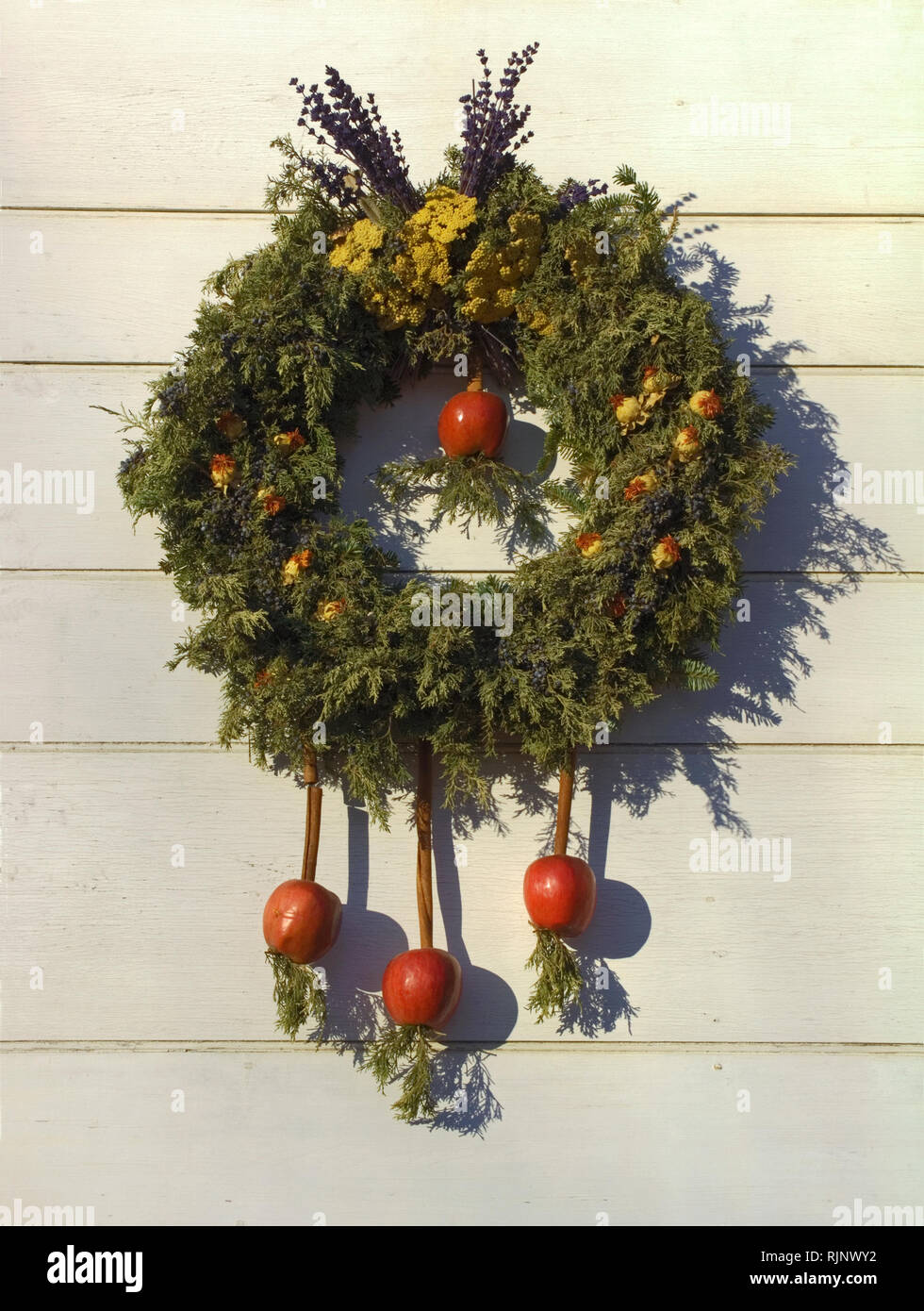 evergreen wreath, natural materials; dangling apples; cinnamon sticks, dried flowers, Christmas; decoration, holiday, festive, unique; winter; vertica Stock Photo