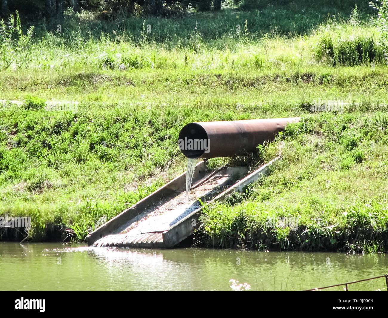 Water flows from a large pipe into the pond. Water flows from a large