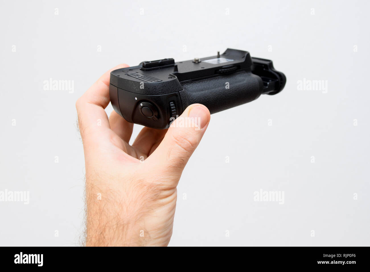 Photographer hand holding against white background a battery camera grip for his new camera Stock Photo