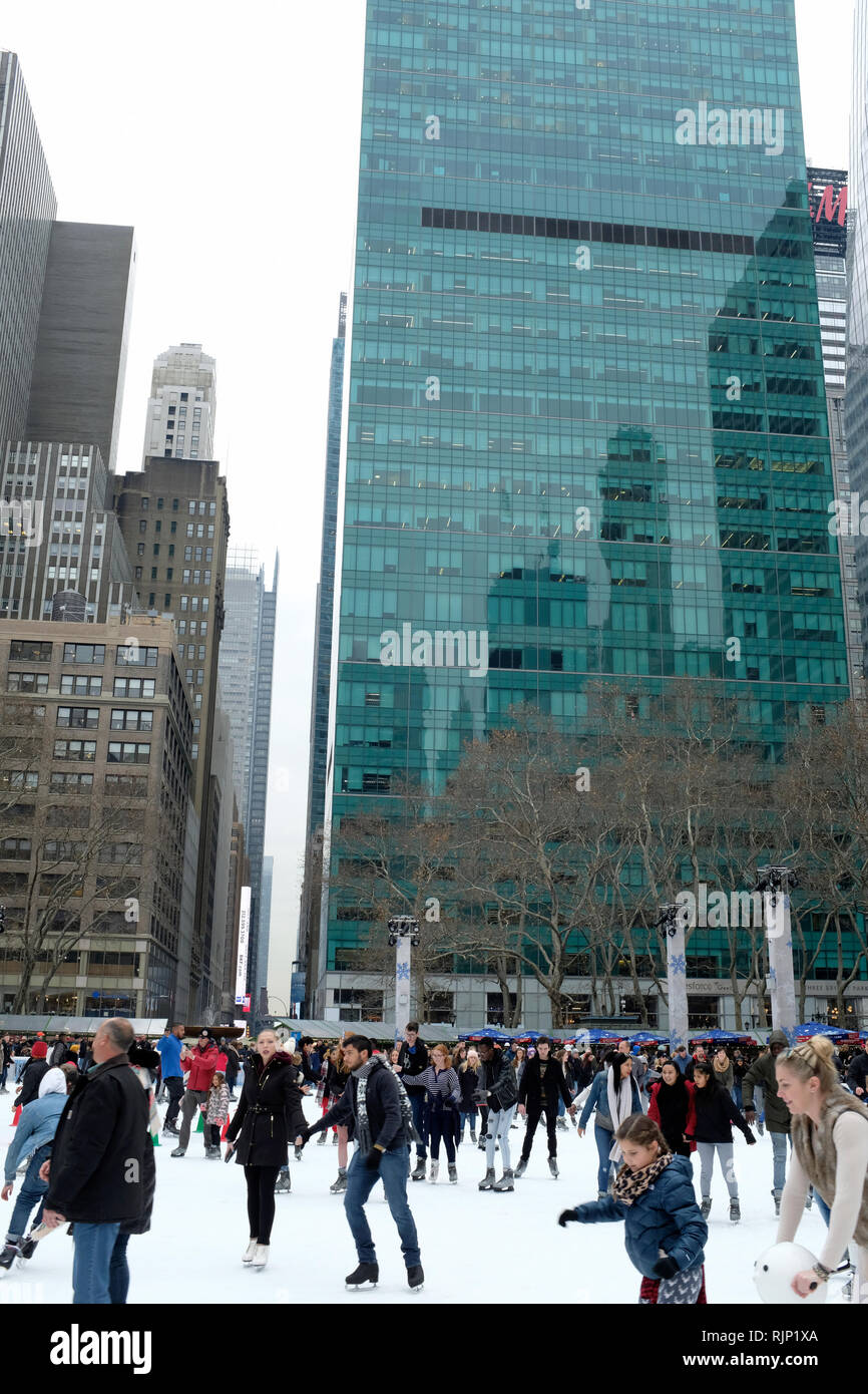 People skating at Bryant Park during holiday season with office towers in Midtown Manhattan in the background. New York City.NY.USA Stock Photo