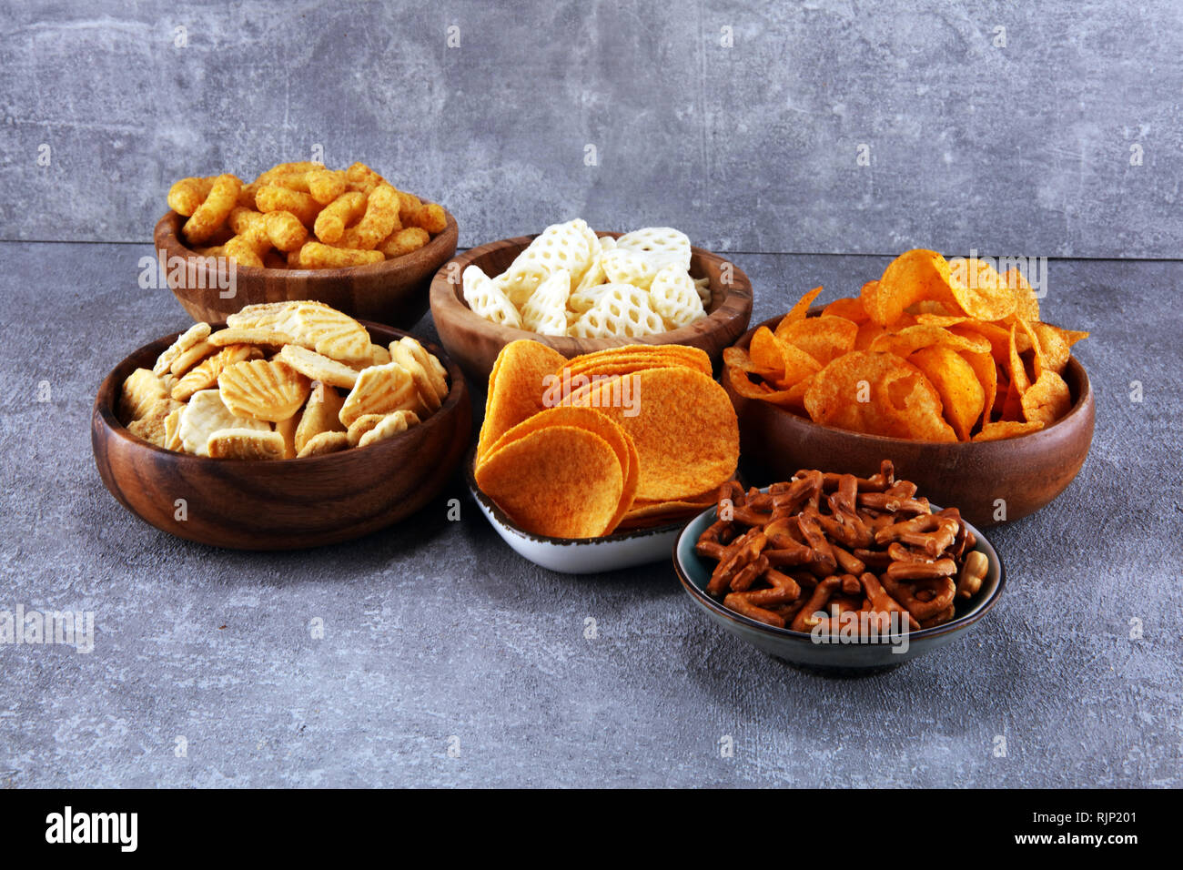 Salty snacks. Pretzels, chips, crackers in wooden bowls. Unhealthy