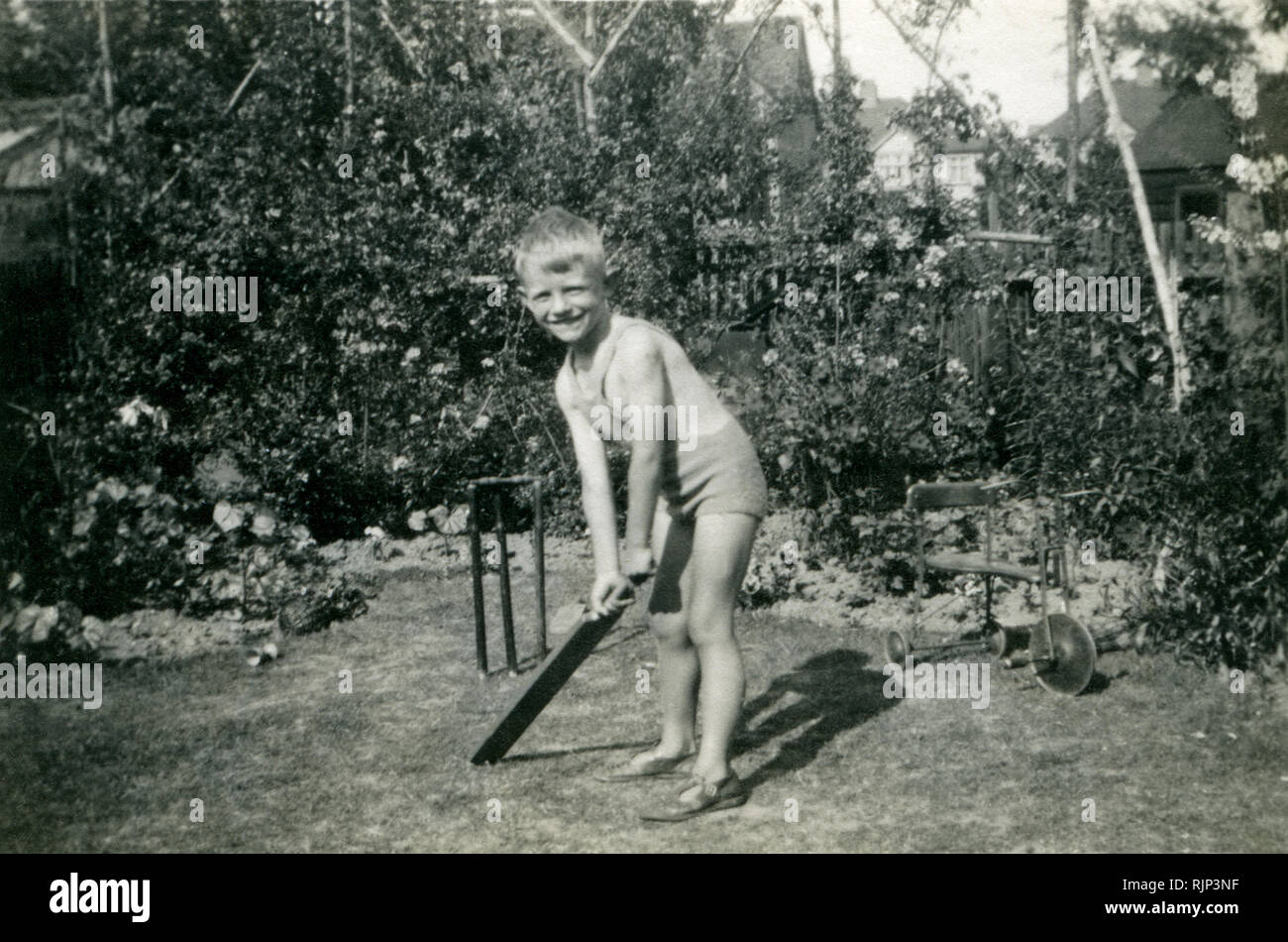 Young boy, four years old, playing cricket in suburban family garden, 1938 Stock Photo