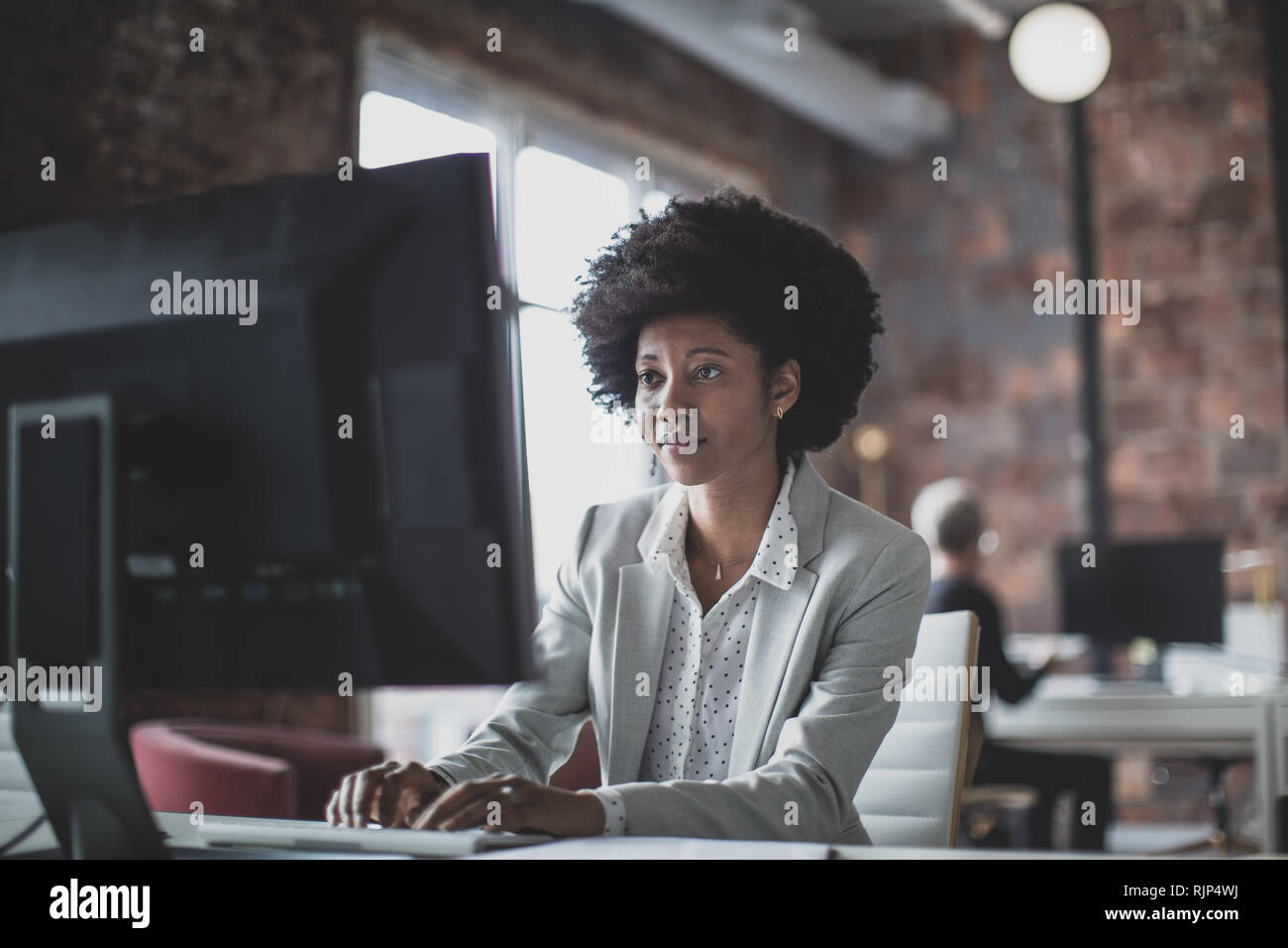 Female african american business executive working in an office on a desktop computer Stock Photo