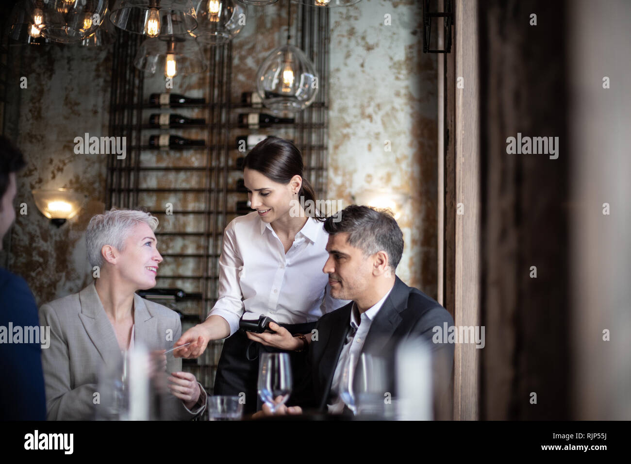 Waitress taking payment in a restaurant Stock Photo