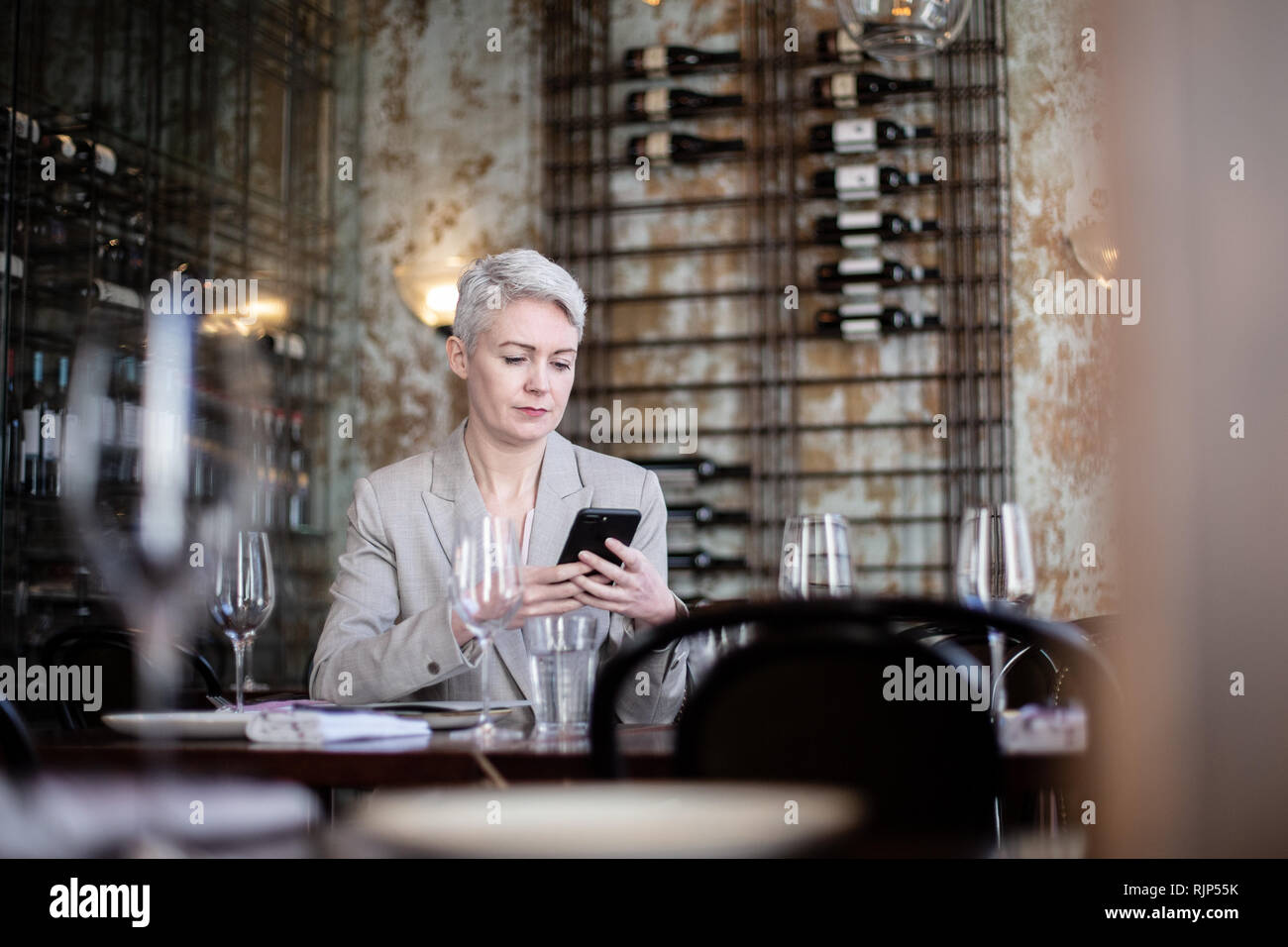 Businesswoman using smartphone in a restaurant Stock Photo