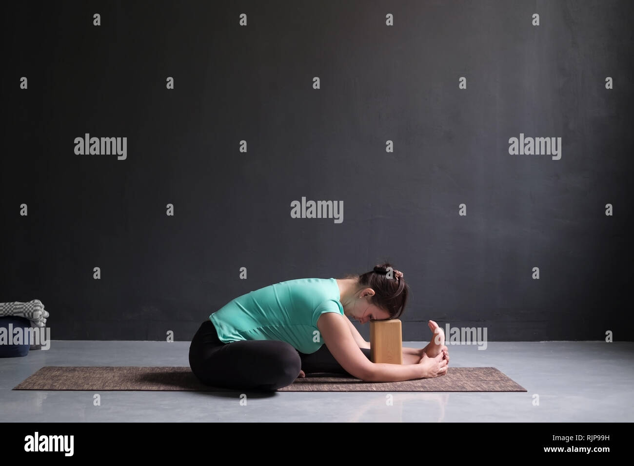woman practicing yoga, Seated forward bend pose , using brick or block Stock Photo