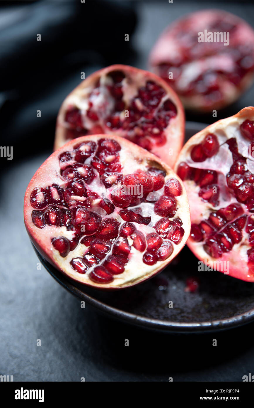 Ripe cut pomegranate on a slate plate. Red and dark colors composition Stock Photo