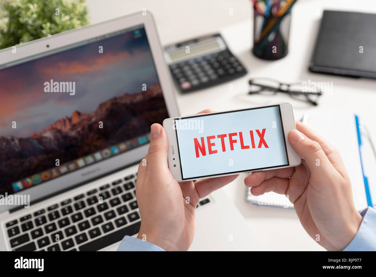 Wroclaw, Poland - JAN 31, 2019: Man holding smartphone with Netflix logo. Netflix is a global provider of streaming movies and TV series Stock Photo