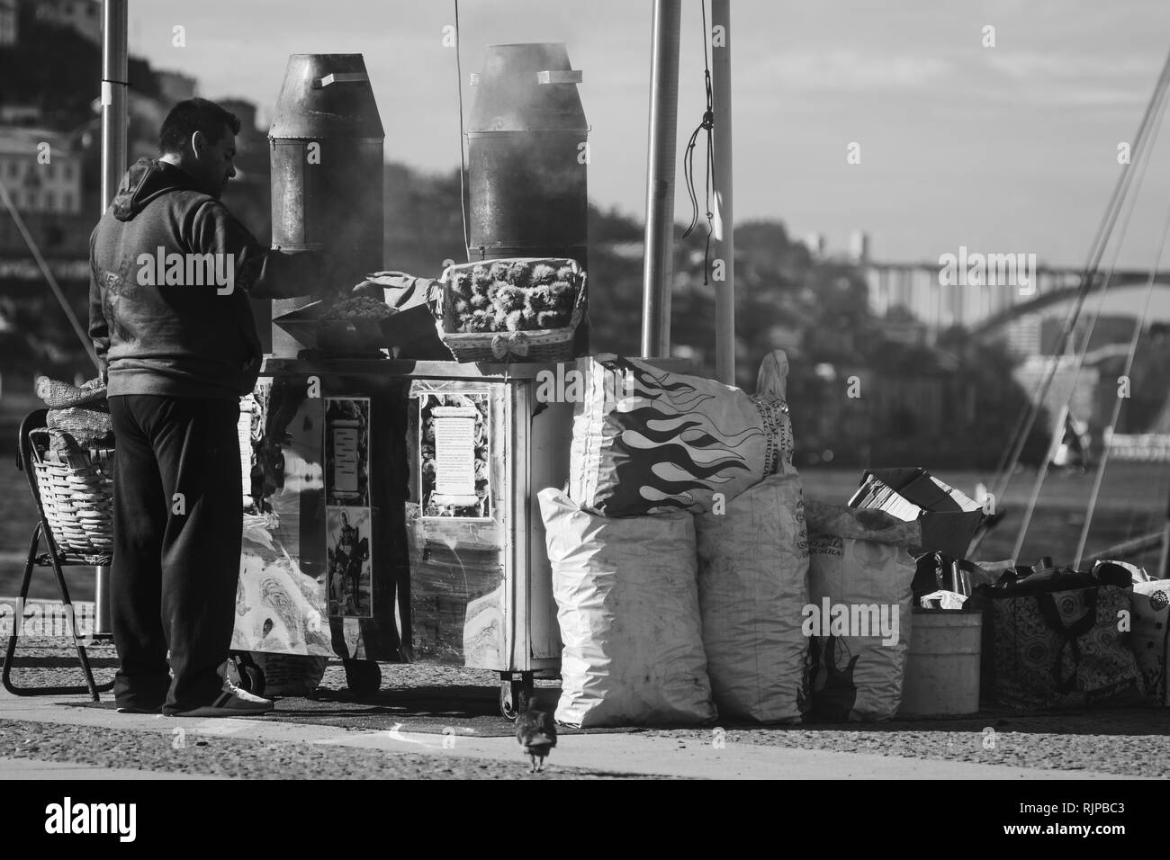 chestnut seller in black and white with city in the background Stock Photo