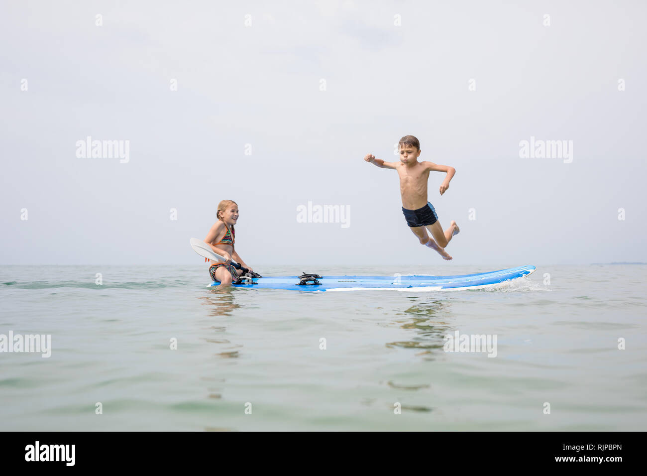 Happy children playing on the beach at the day time. Two Kids having fun outdoors. Concept of summer vacation and friendly family. Stock Photo
