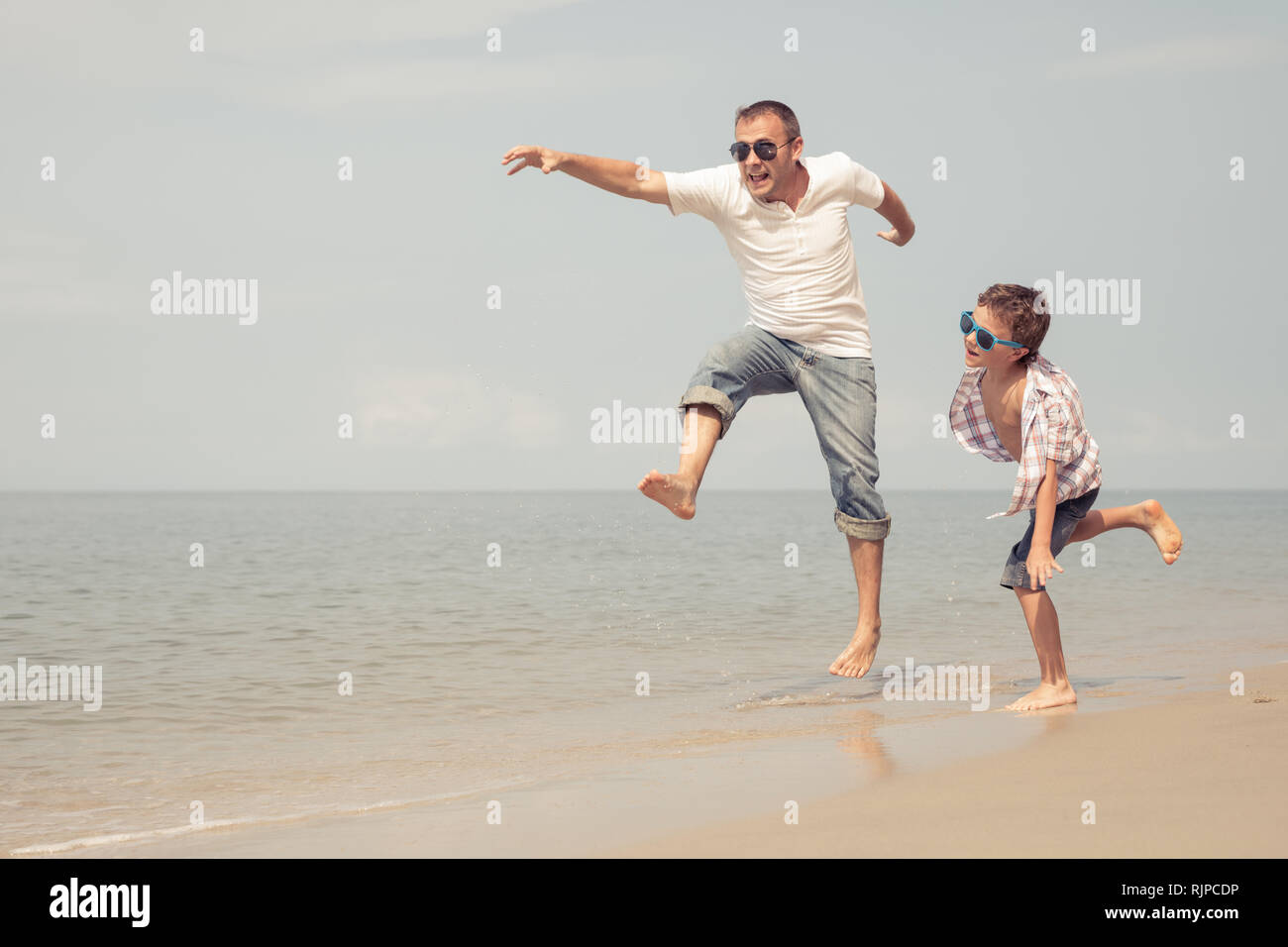 Father and son playing on the beach at the day time. People having fun outdoors.  Concept of happy vacation and friendly family. Stock Photo