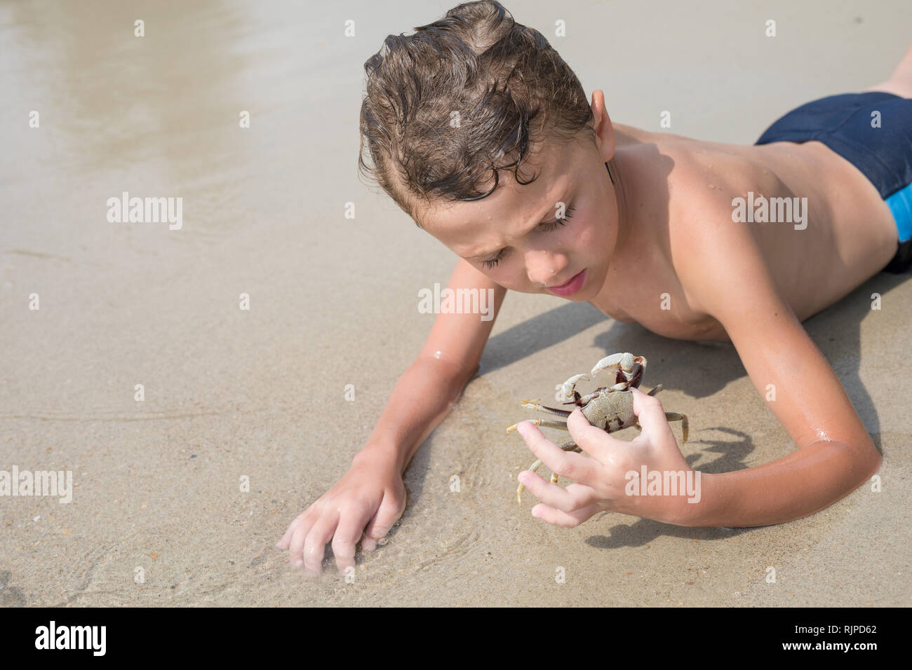 One happy little boy playing on the beach at the day time.  Kid having fun outdoors. Concept of summer vacation. Stock Photo