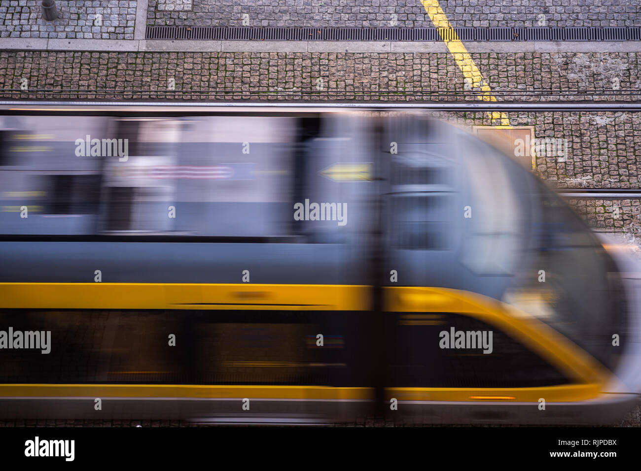 electric black and yellow tram in an old street in the city center Stock Photo