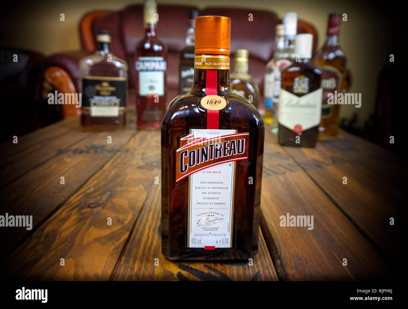 Alcoholic french ligueur cointreau outstanding on wooden table with other alcoholic beverages illustrative editorial Stock Photo