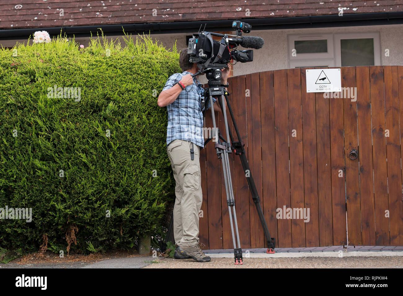A television camera man films over the garden gate of mafia boss Domenico Rancadore, wanted on a European arrest warrant. London. August 9, 2013. Stock Photo