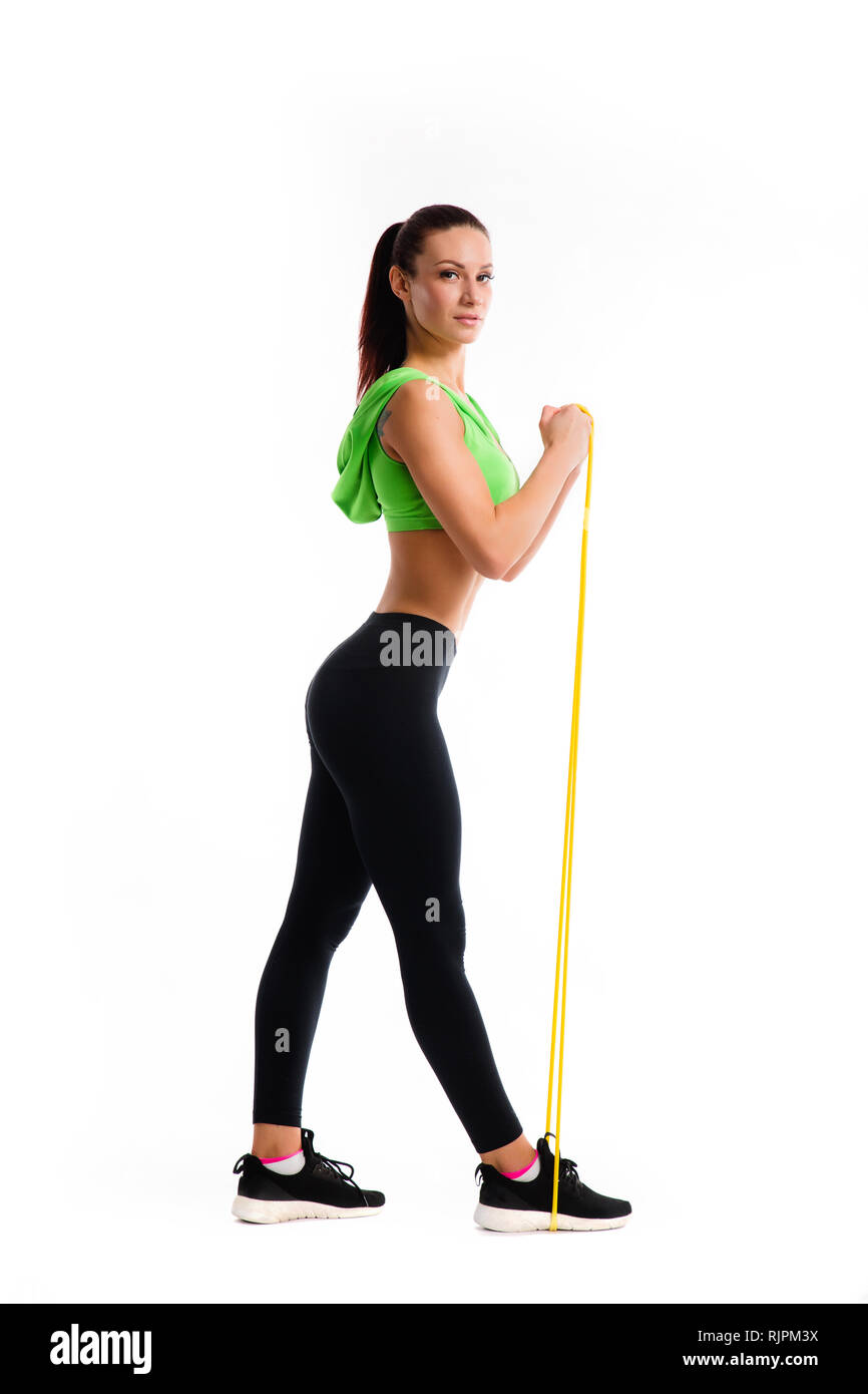 Athletic girl working with resistance band. Photo of attractive latin girl with beautiful athletic body isolated on white background. Stock Photo