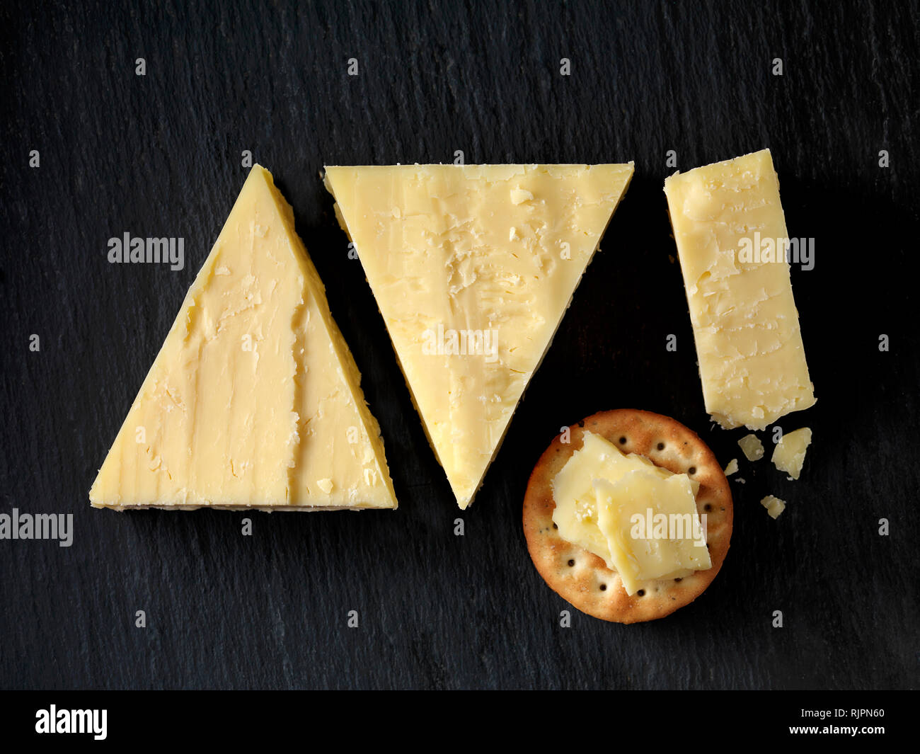 Still life with cheese cracker and cheddar cheese triangles on black
