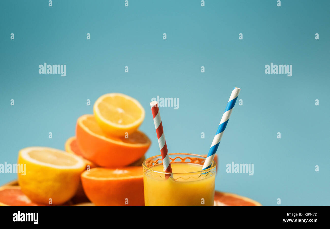 cut in half juicy citruses on a blue background on a tray next to a glass of fresh tasty juice Stock Photo