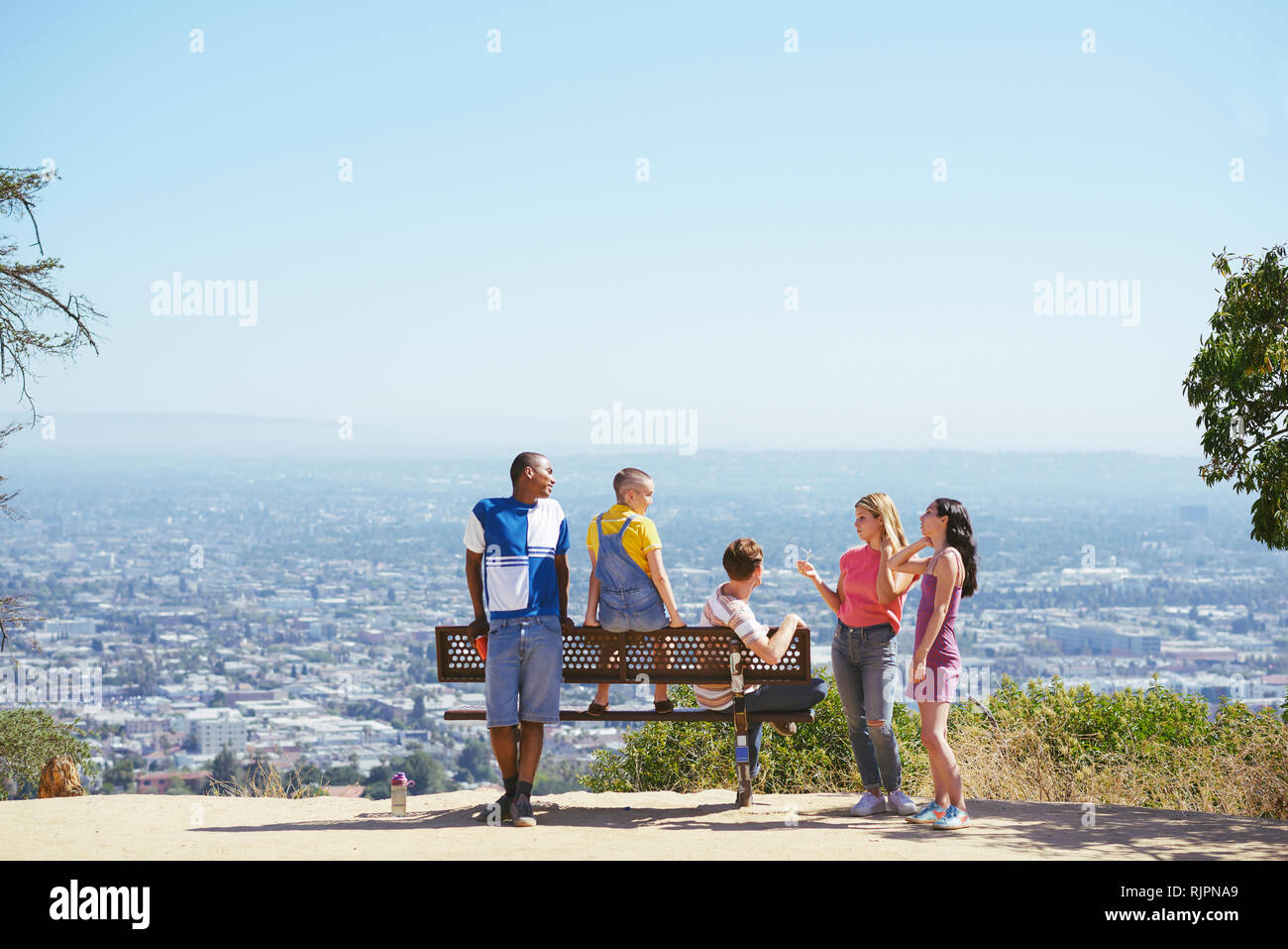 Five young adult friends on cityscape hilltop bench, rear view, Los Angeles, California, USA Stock Photo