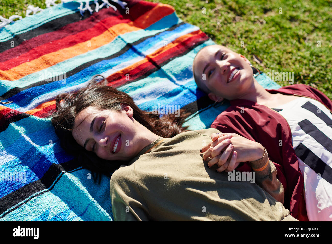 Two young female friends lying on picnic blanket in park, Los Angeles, California, USA Stock Photo