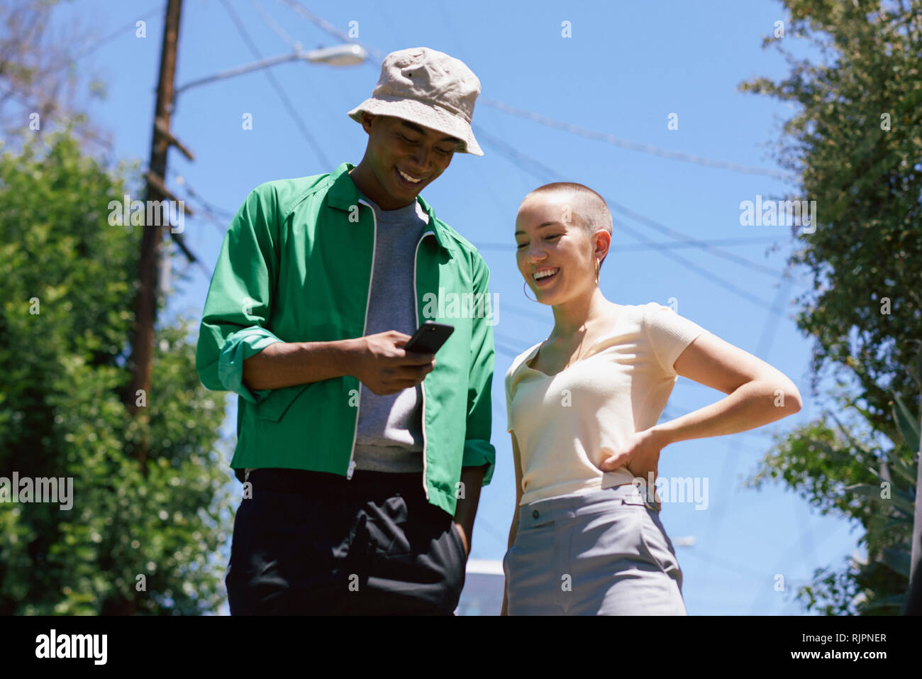 Young man and female friend looking at smartphone in suburbs, Los Angeles, California, USA Stock Photo