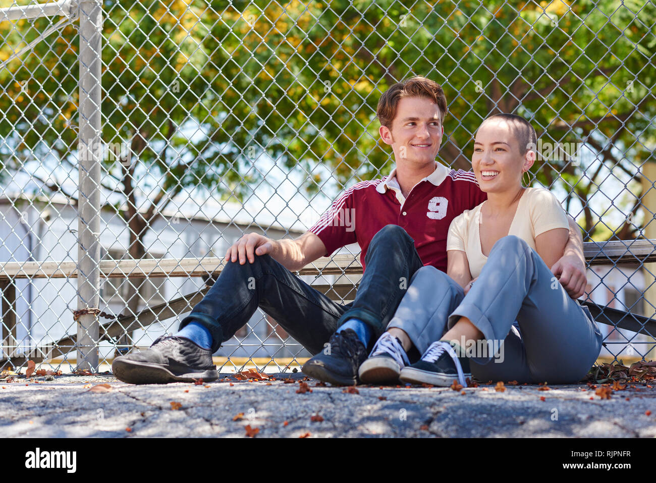 Young couple sitting by park fence, Los Angeles, California, USA Stock Photo