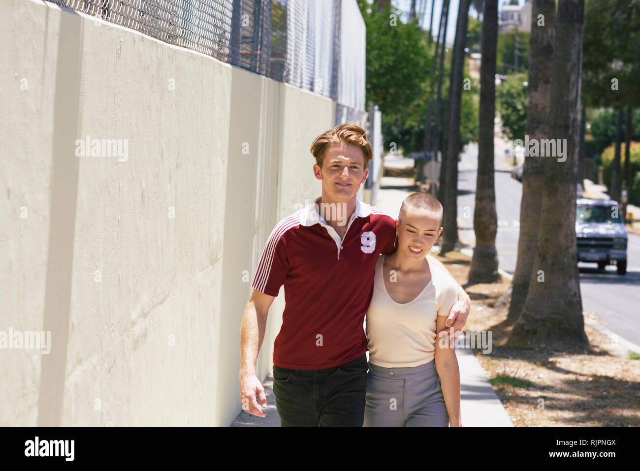 Young man and girlfriend strolling on suburban sidewalk, Los Angeles, California, USA Stock Photo