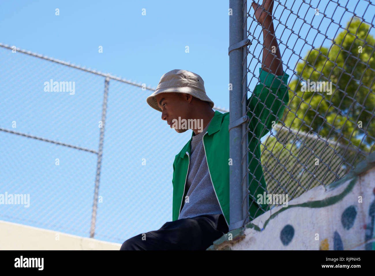 Young man looking out from park fence, low angle view, Los Angeles, California, USA Stock Photo