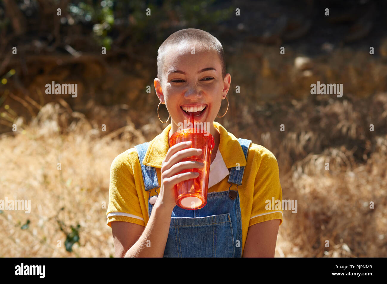 Teenage girl with cropped hair drinking from takeaway cup in park, Los Angeles, California, USA Stock Photo