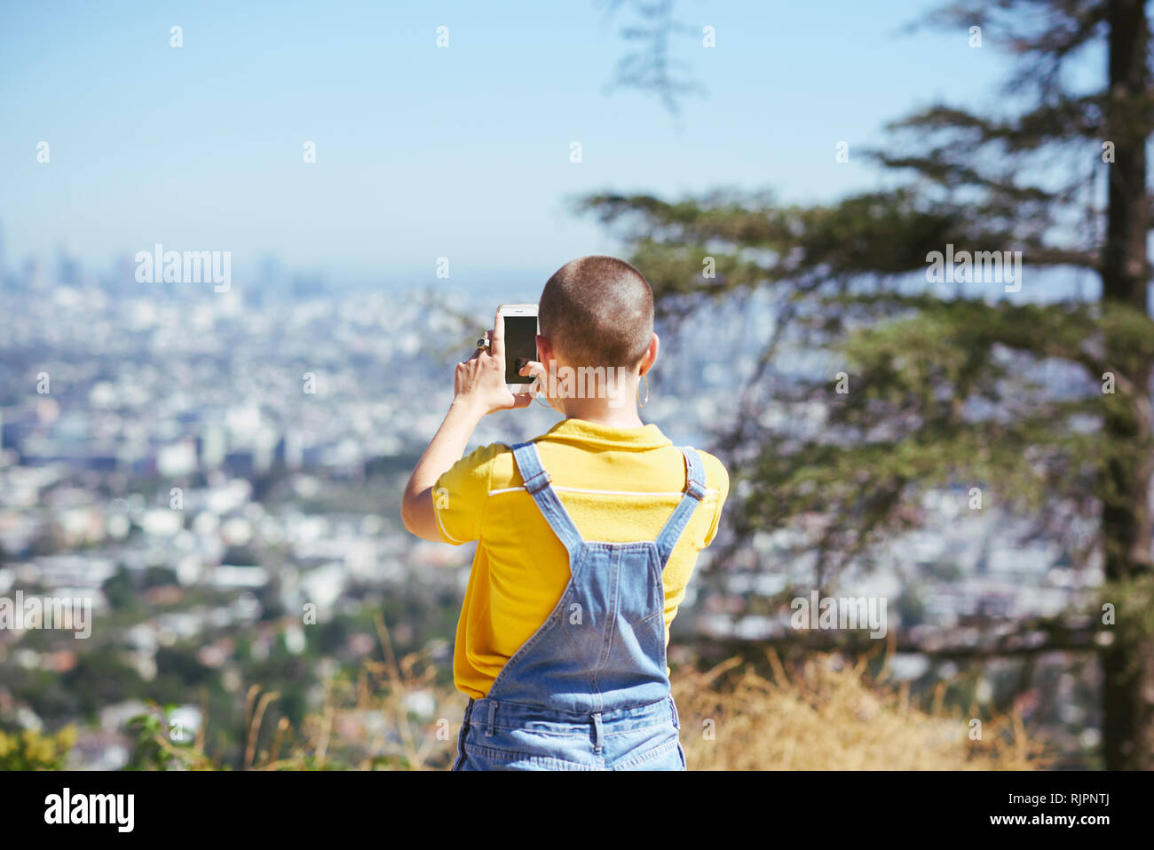 Teenage girl photographing view from cityscape hilltop, Los Angeles, California, USA Stock Photo