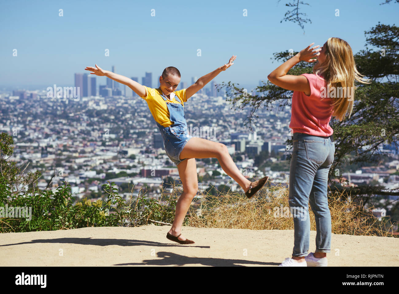 Two young female friends having fun on cityscape hilltop, Los Angeles, California, USA Stock Photo
