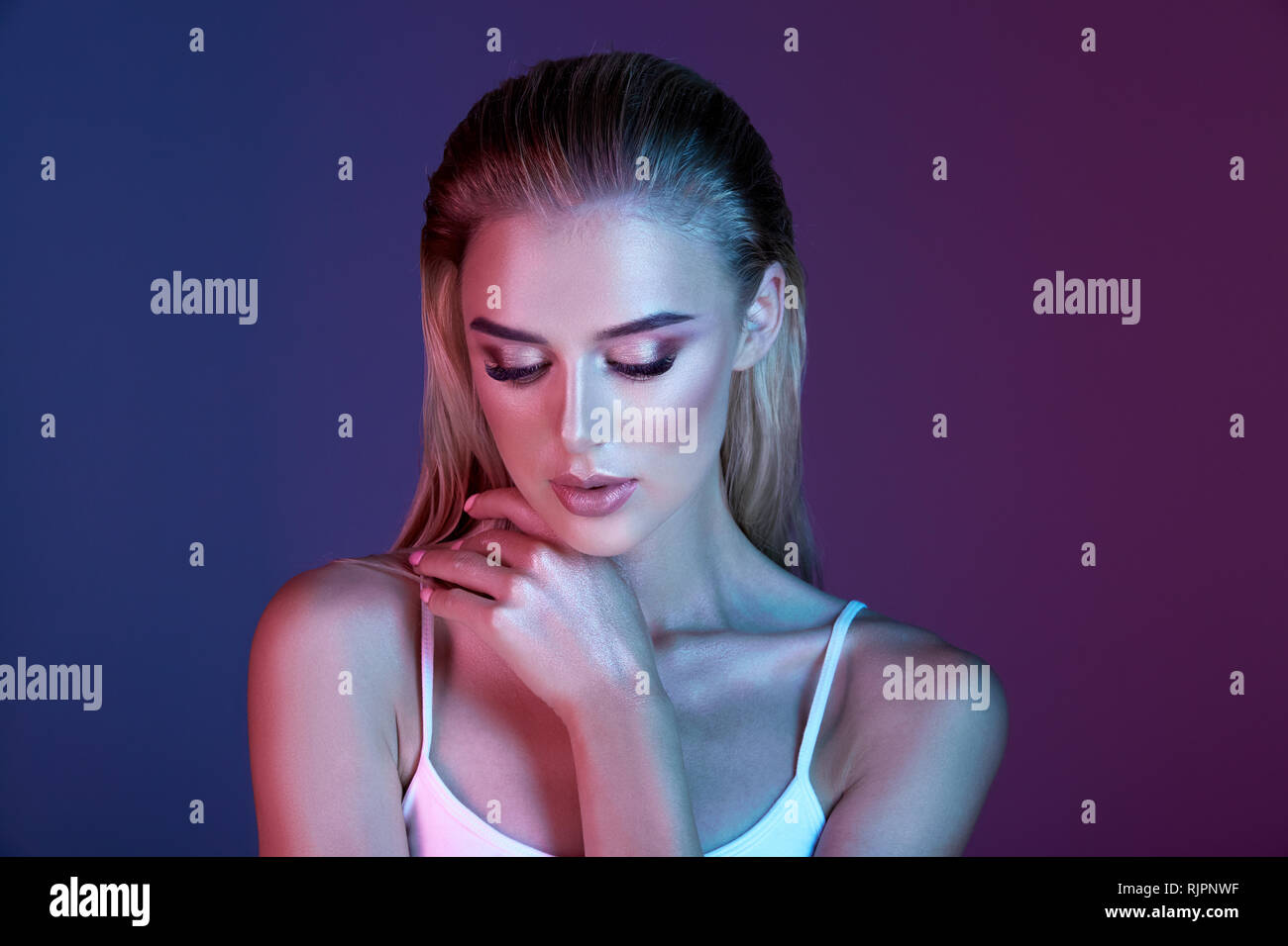 Pretty Girl With Make Up And Blonde Hair Posing With At Dark Blue