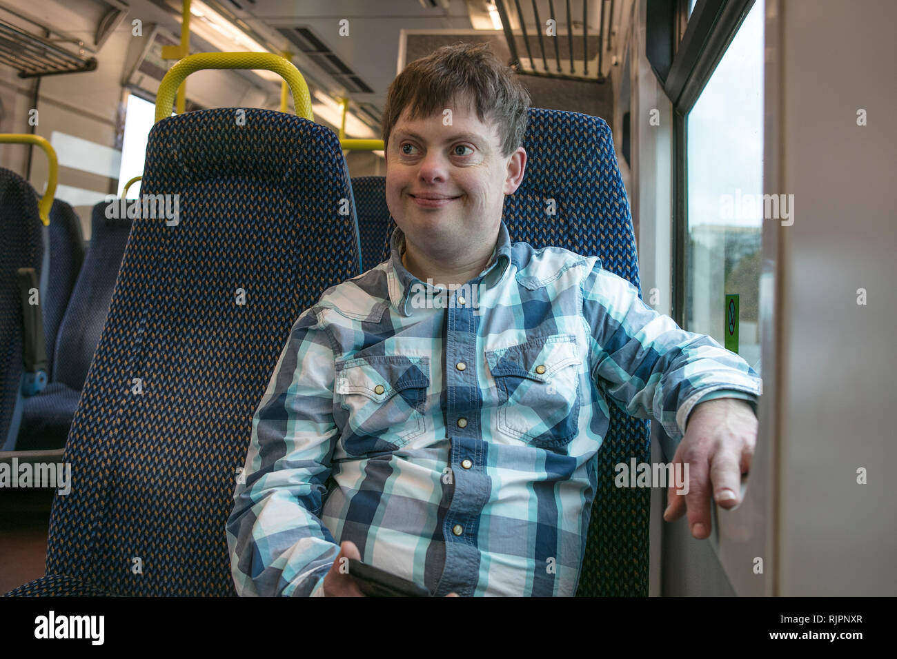 Man with down syndrome with cell phone on train Stock Photo