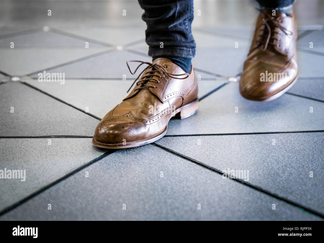Feet in pair of brogues on tiled flooring Stock Photo