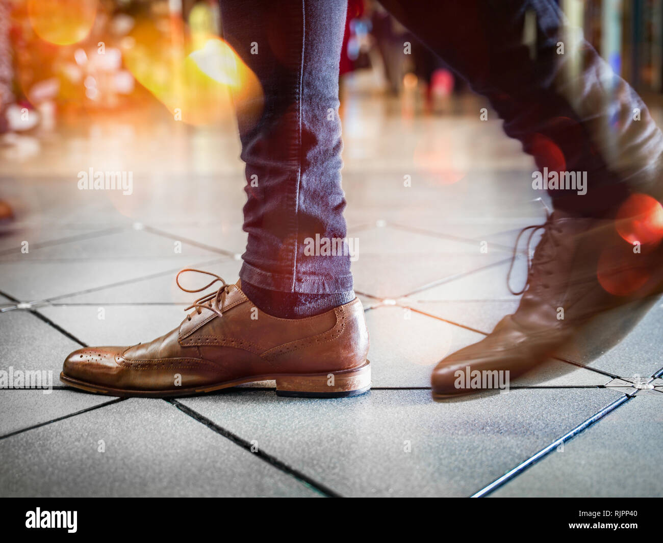 Feet in pair of brogues on tiled flooring Stock Photo